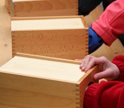 Kinder spielen mit Holzboxen