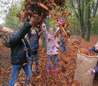 Kinder spielen mit Laub